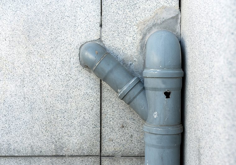 drain pipe with a hole in it on the side of a house