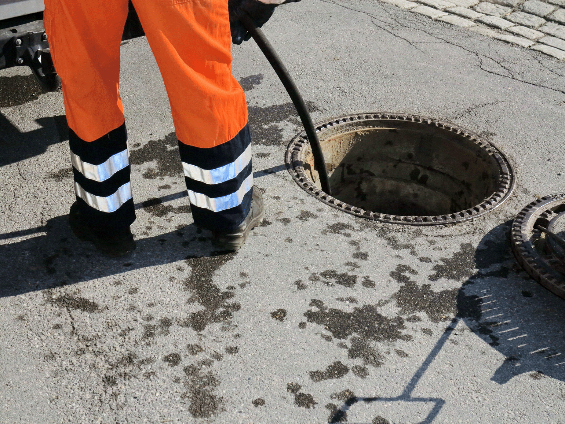 plumber in work trousers unblocking a drain
