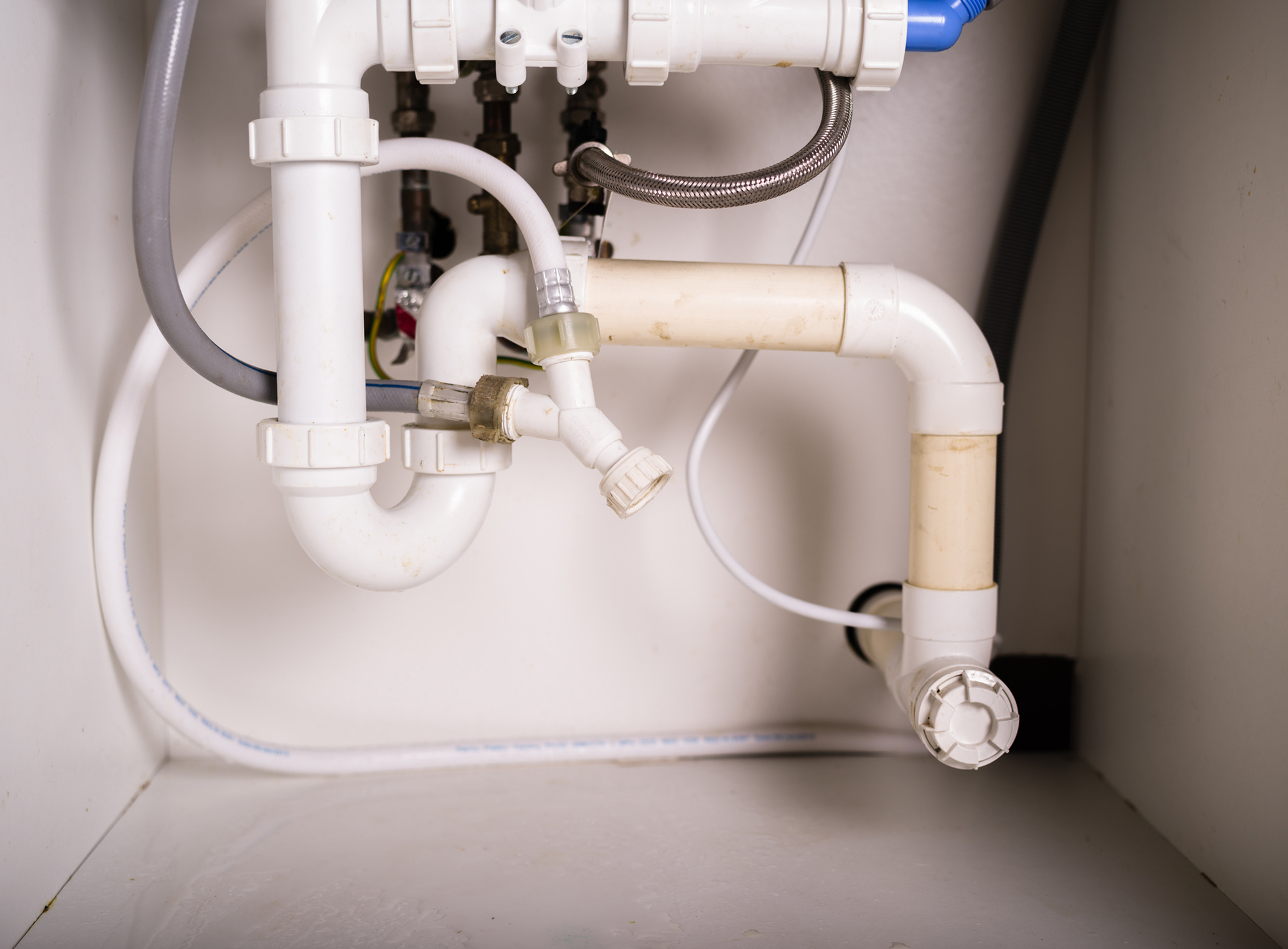 White pipes in a cupboard under the sink
